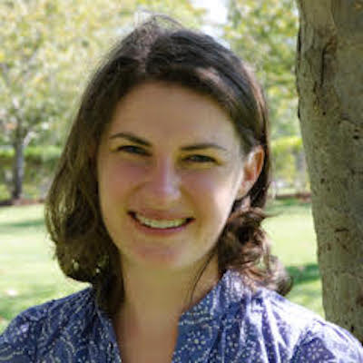 Headshot of Erin Sigel standing in front of green lawn
