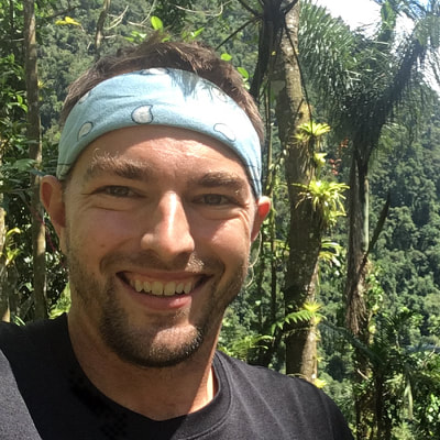 Headshot of Nic Kooyers wearing blue bandana with tropical forest background
